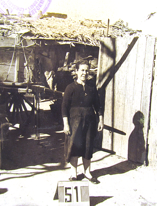 El tiempo ha permitido que las imgenes destinadas a identificar a los habitantes con sus viviendas, dejen al descubierto otros detalles de gran valor. Por ejemplo, la foto de esta vecina tomada frente a una chabola del Barrio de la Celsa, permite ver tras ella un carro de madera destinado al tiro de animales. ( Foto: JJMANCHA / Vallecasweb.com)